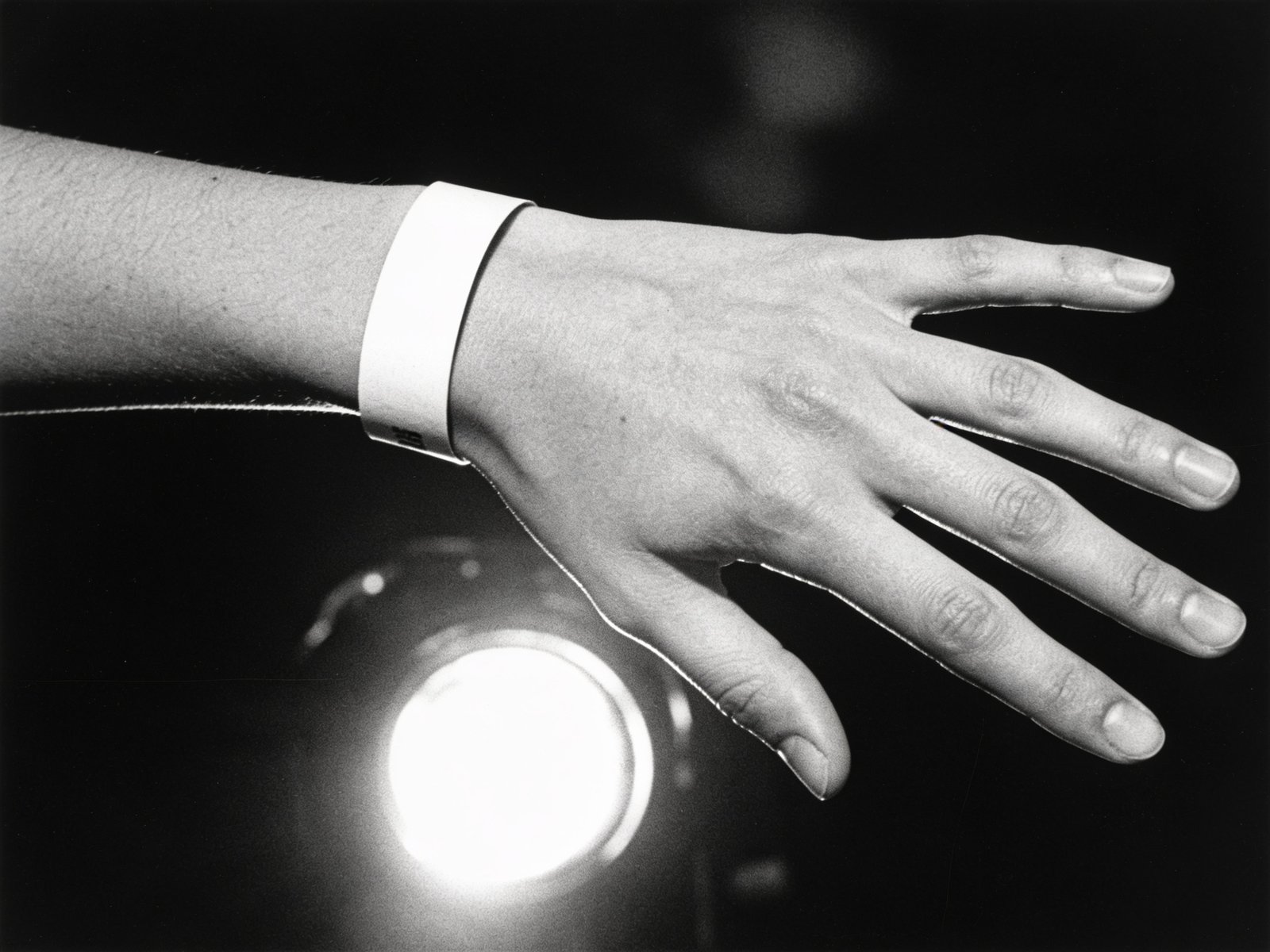 Event wristband on a wrist reaching toward the light