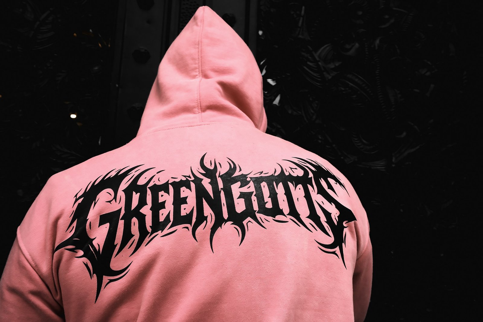 Pink hoodie against a black iron door